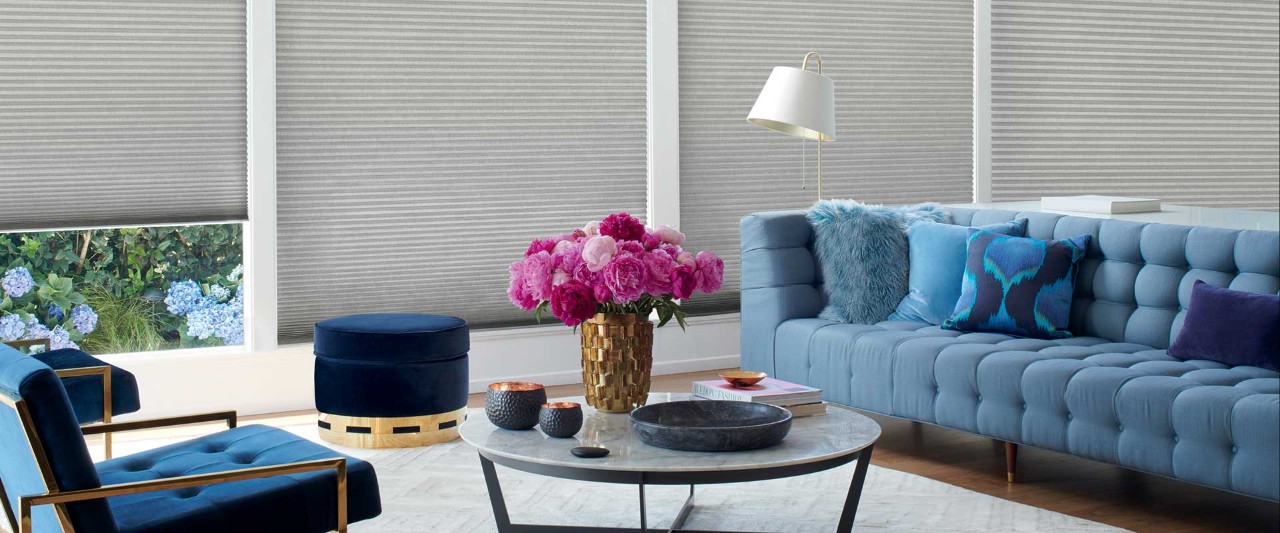 Living room with blue couch and pink flowers on coffee table.