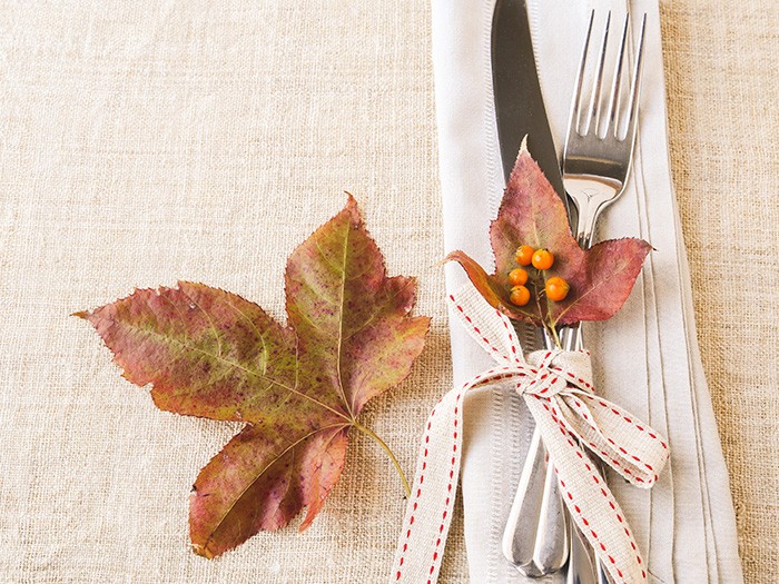Dried maple leaves with silverware and beige linen